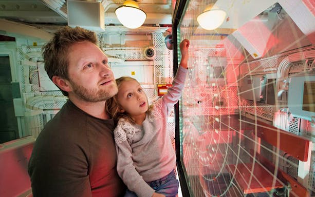 Father and daughter exploring radar room on HMS Belfast.