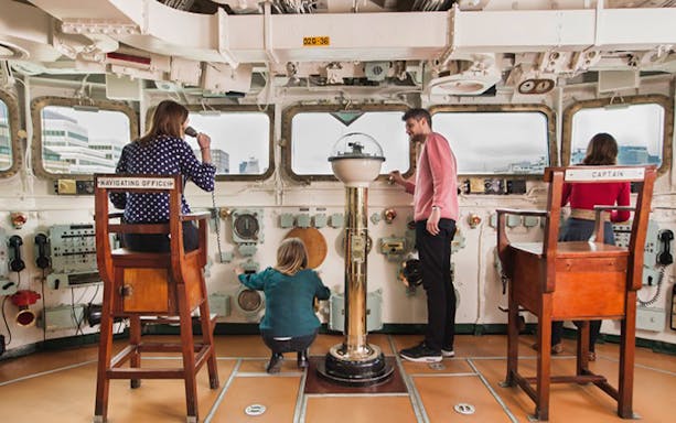 Visitors exploring the navigation room on HMS Belfast in London.