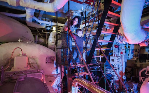 Visitors exploring the engine room of HMS Belfast in London.
