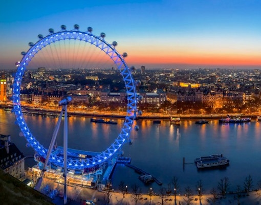 London Eye illuminated at dusk with cityscape and River Thames view.