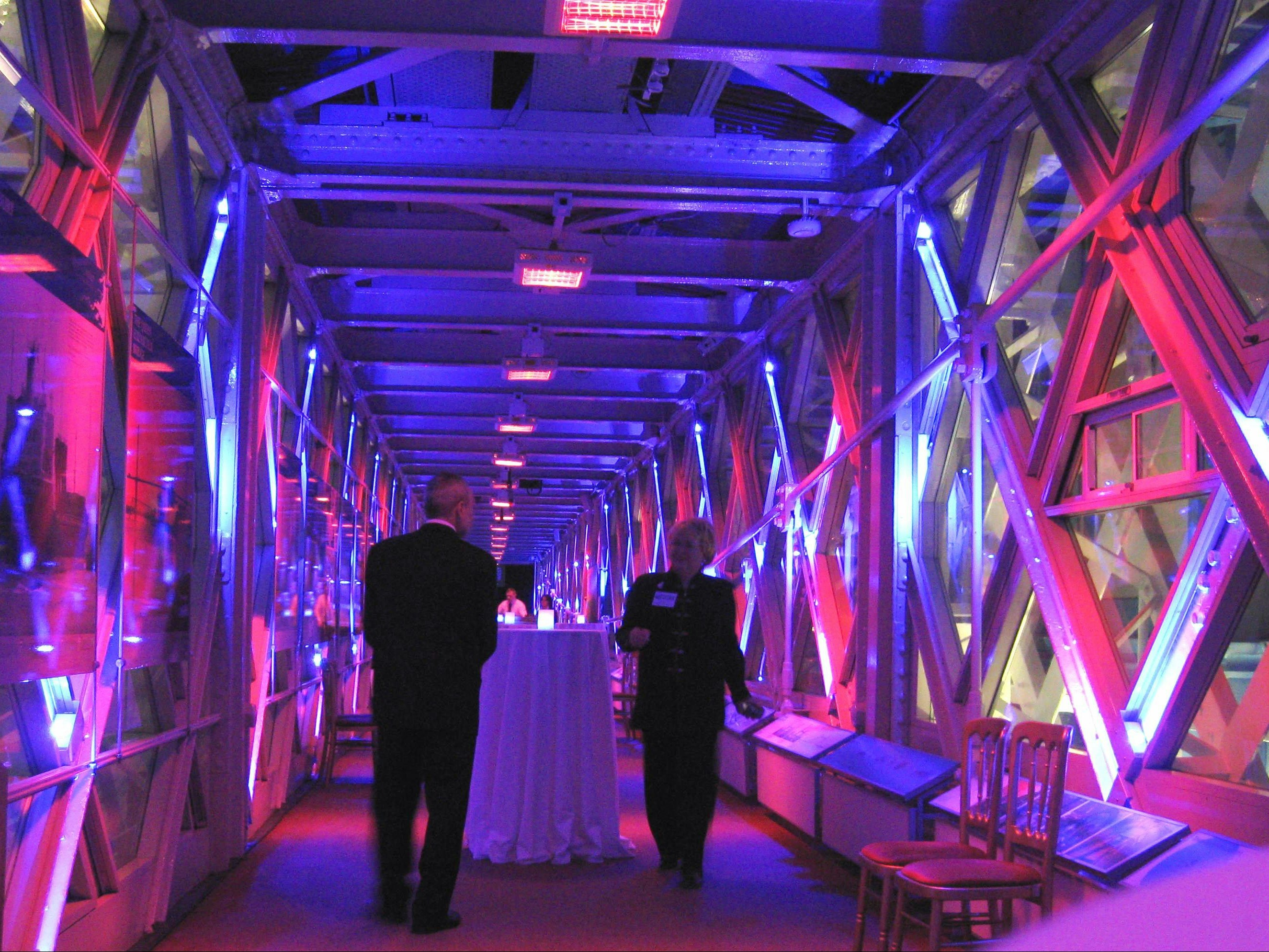 Visitors inside the illuminated walkway of Tower Bridge, London.