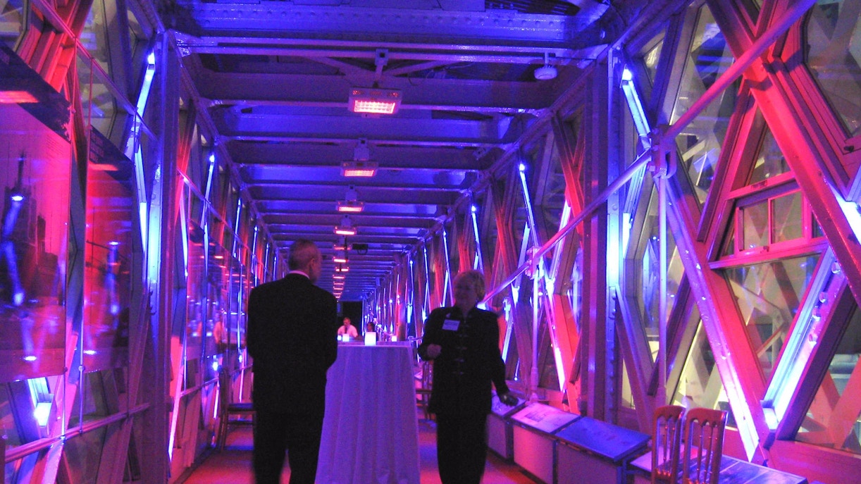 Visitors inside the illuminated walkway of Tower Bridge, London.
