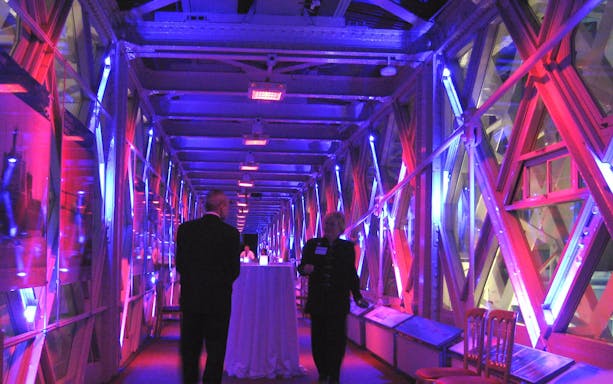 Visitors inside the illuminated walkway of Tower Bridge, London.