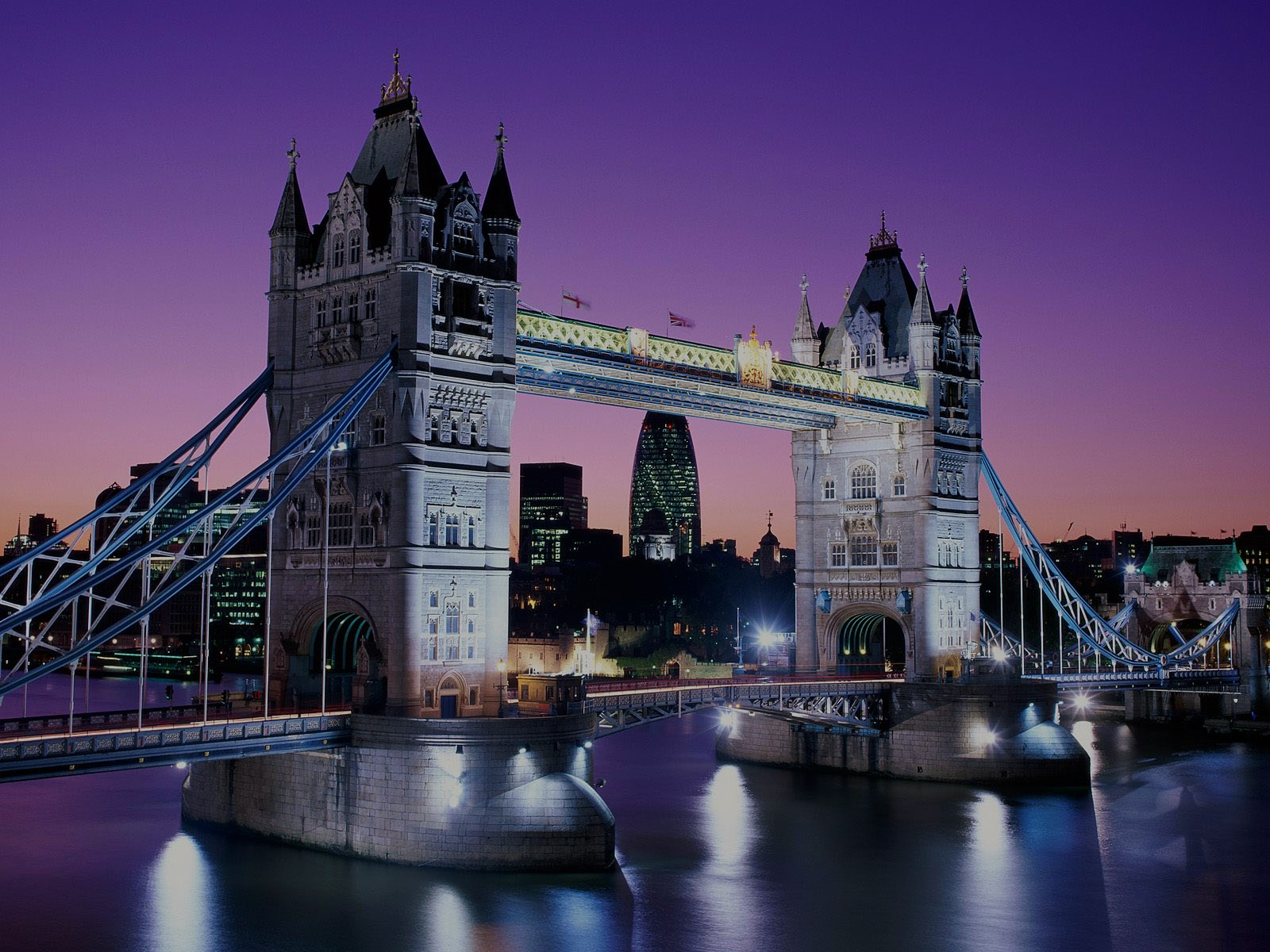 Tower Bridge illuminated at dusk in London, with city skyline in the background.