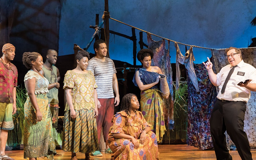 Cast performing a scene from The Book of Mormon in London theater.
