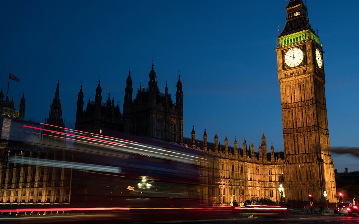 Big Ben and Houses of Parliament illuminated at night with a passing double-decker bus, London.