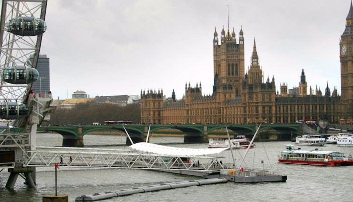 London Eye and Thames River with boats near Westminster Palace.