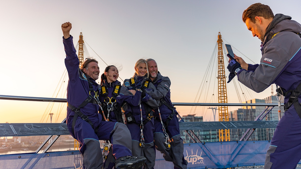 People celebrating on the O2 Arena roof at sunset during Up At The O2 adventure in London.