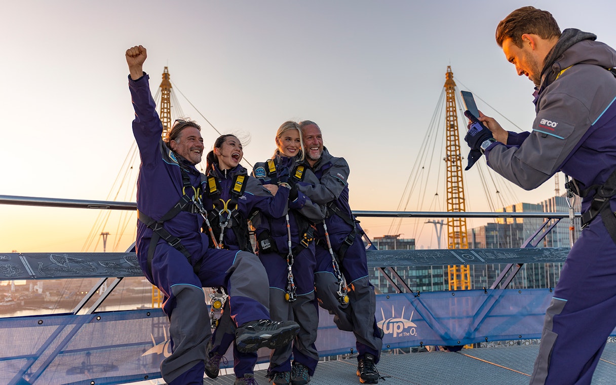 People celebrating on the O2 Arena roof at sunset during Up At The O2 adventure in London.