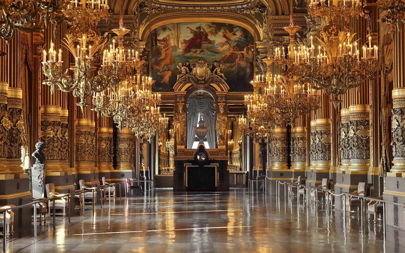 Grand foyer of Opera Garnier with ornate chandeliers and gilded decor, Paris.