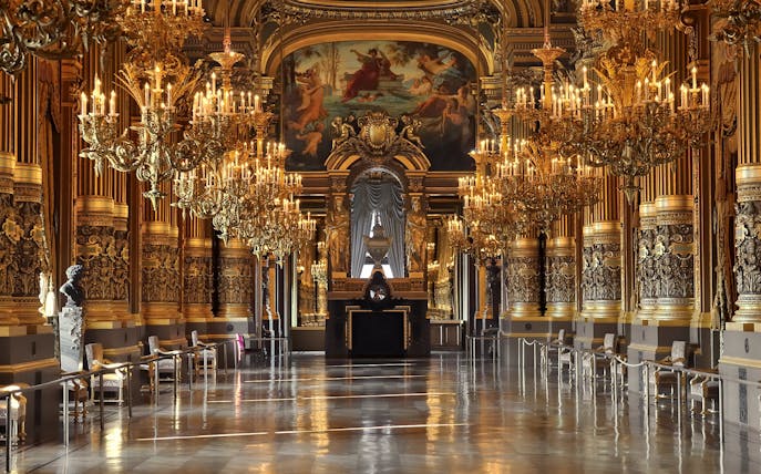 Grand foyer of Opera Garnier with ornate chandeliers and gilded decor, Paris.