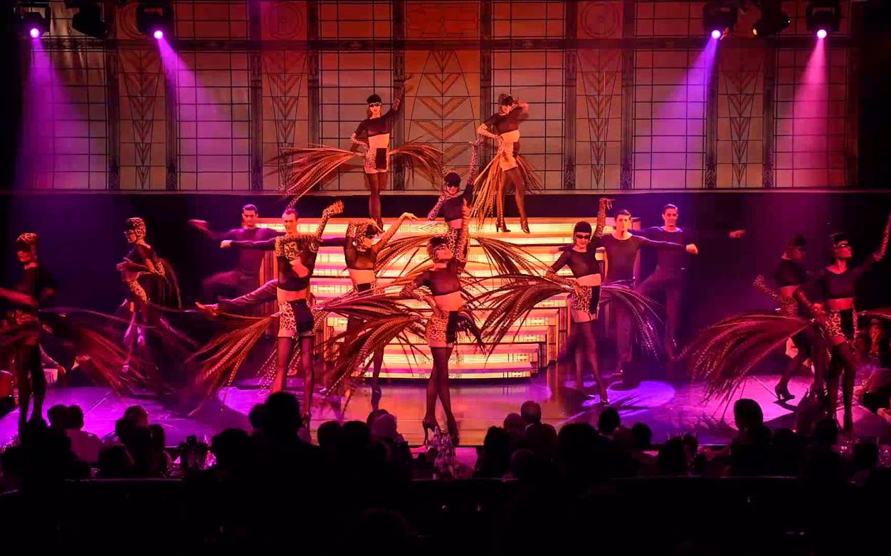 Dancers performing at The Lido Show in Paris with vibrant costumes and stage lighting.