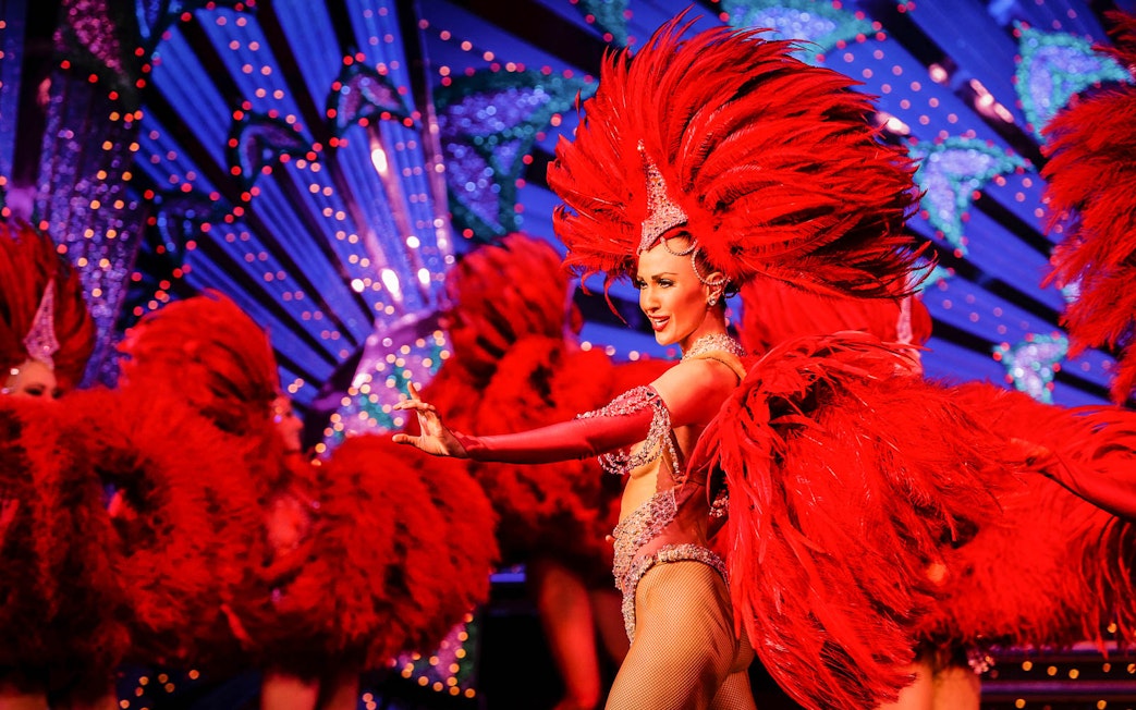Moulin Rouge dancer in red feather costume performing in Paris, France.