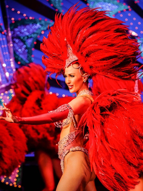 Moulin Rouge dancer in red feather costume performing in Paris, France.