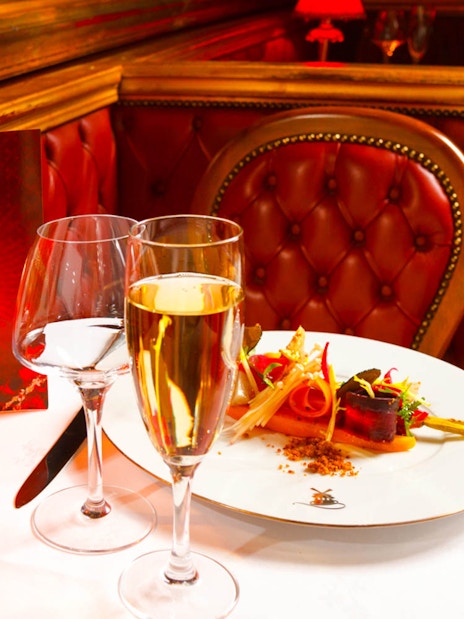 Dinner setting at Moulin Rouge cabaret in Paris with champagne and gourmet dish.