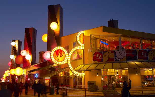 Café Mickey at Disneyland Paris illuminated at night with colorful lanterns.
