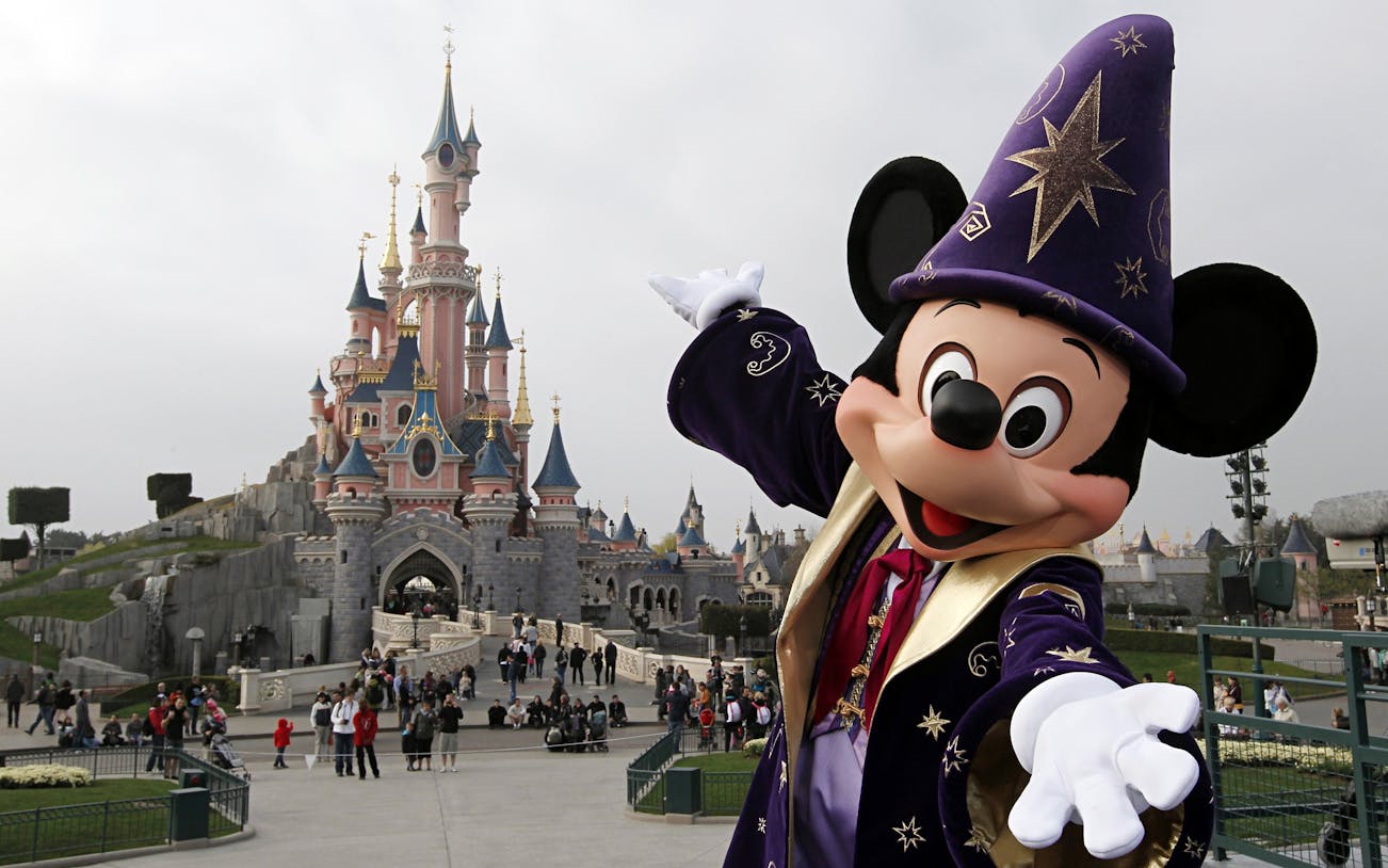 Disneyland Paris castle with character in wizard costume welcoming visitors.