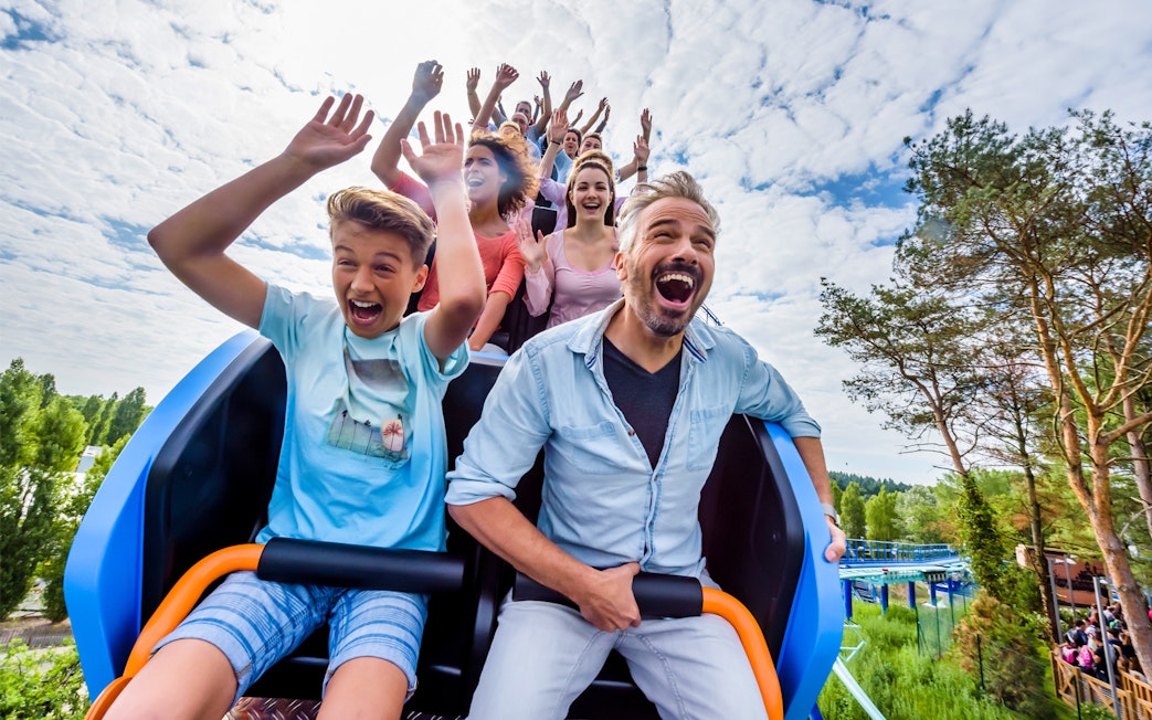 Visitors on a roller coaster at Astérix Park, Paris, enjoying the ride with raised hands.