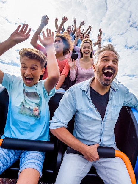 Visitors on a roller coaster at Astérix Park, Paris, enjoying the ride with raised hands.