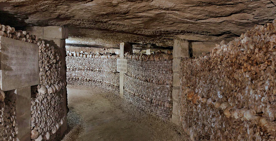 Paris Catacombs tunnel lined with skulls and bones.