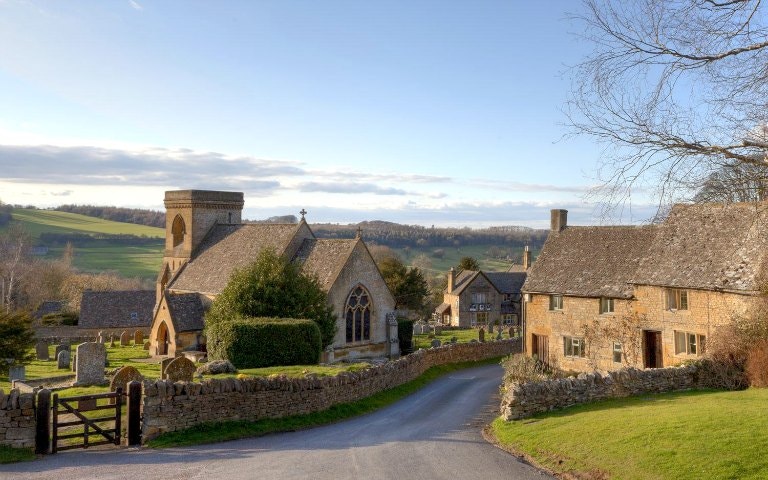Cotswolds village with stone cottages and church, part of Downton Abbey filming locations tour.