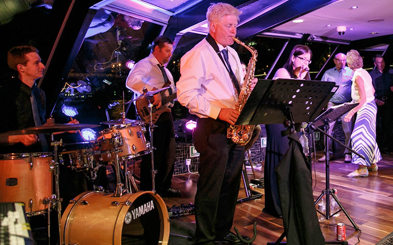 Jazz band performing on Thames River cruise at night.