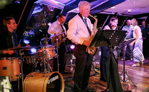 Jazz band performing on Thames River cruise at night.