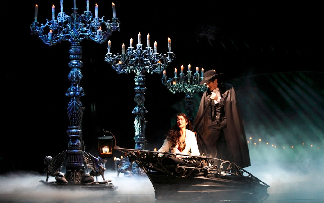 Phantom of the Opera scene with characters in a boat surrounded by candelabras.