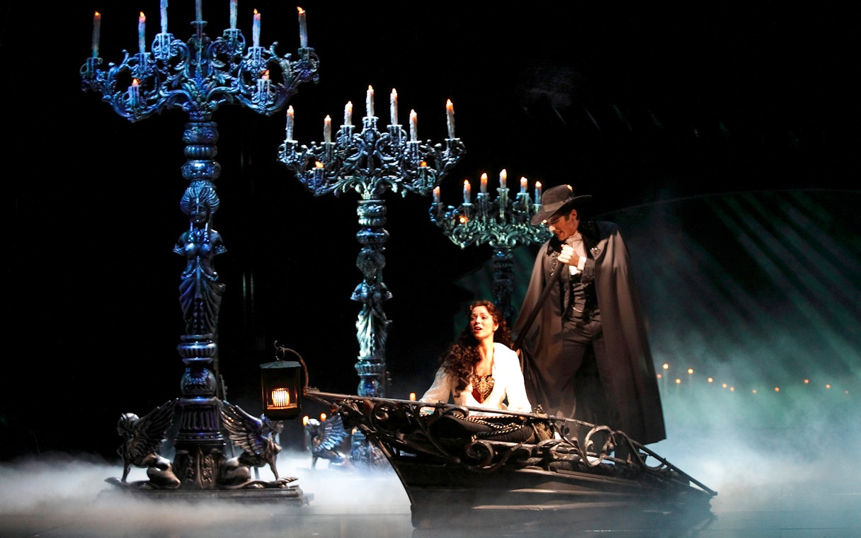 Phantom of the Opera scene with characters in a boat surrounded by candelabras.