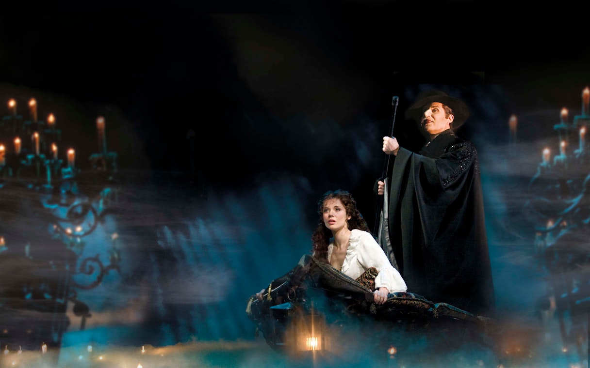 Phantom of the Opera scene with characters on a boat surrounded by candlelight.