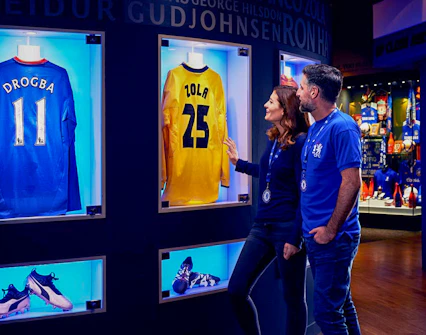 Chelsea FC fans viewing Drogba and Zola jerseys at the stadium museum.
