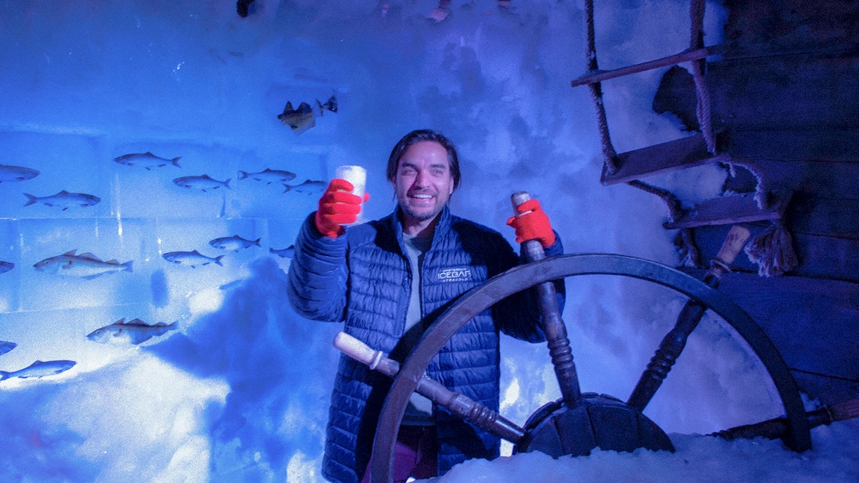 Man enjoying drinks at Xtracold Icebar Amsterdam, holding a steering wheel in icy surroundings.