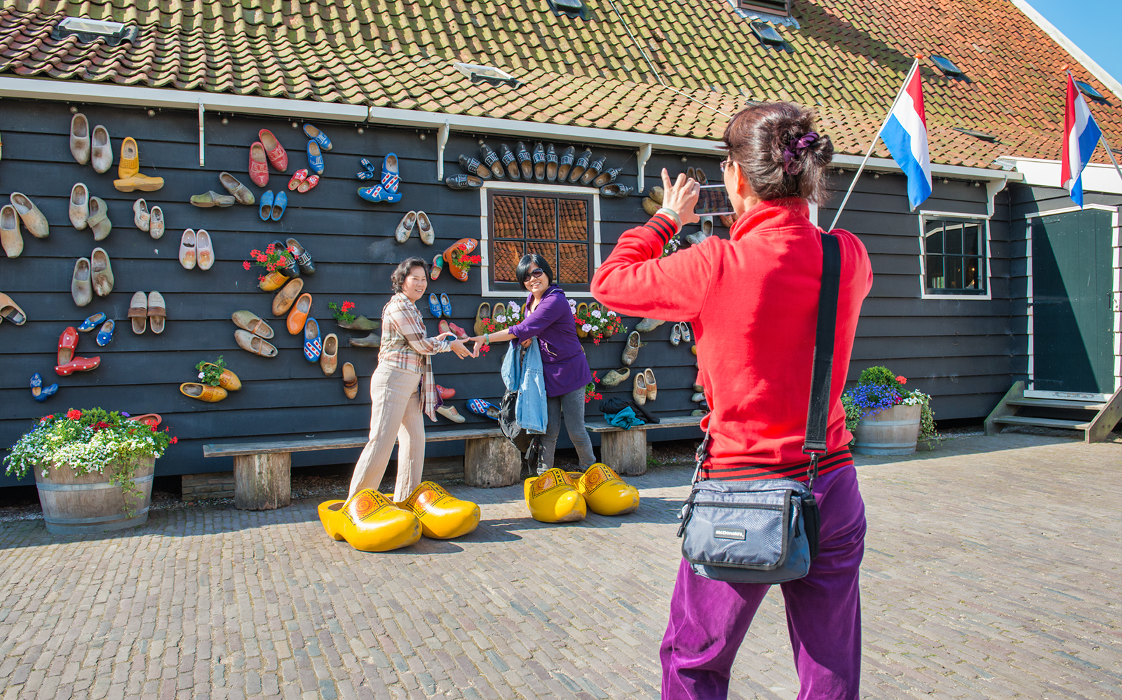 Visitors posing with giant clogs at a traditional Dutch house in Volendam.
