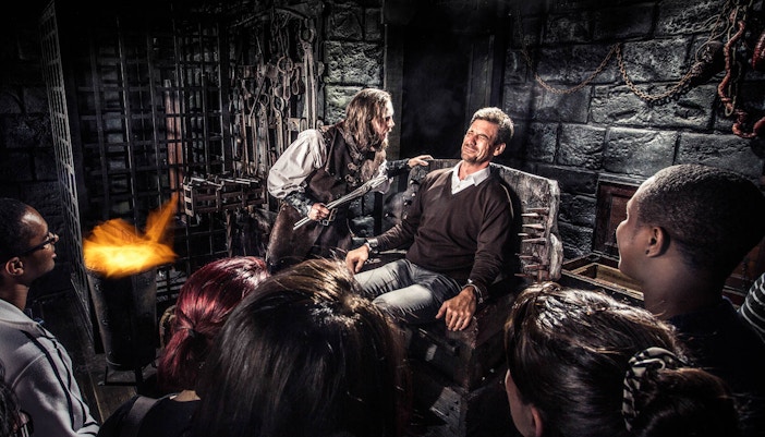 Group watching a theatrical torture scene at Amsterdam Dungeon.