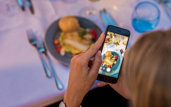 Guest photographing dinner on a cruise with a smartphone.
