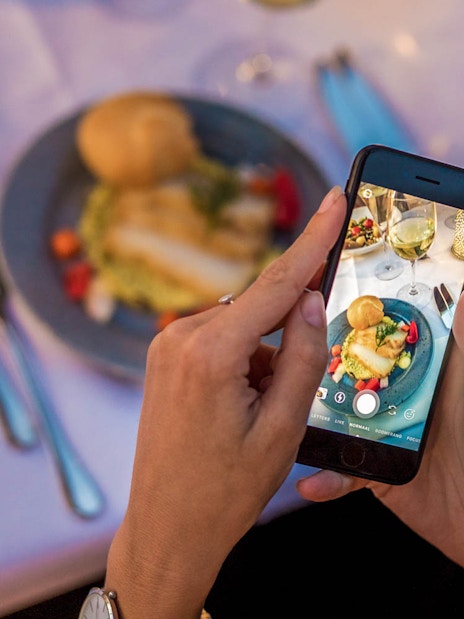 Guest photographing dinner on a cruise with a smartphone.