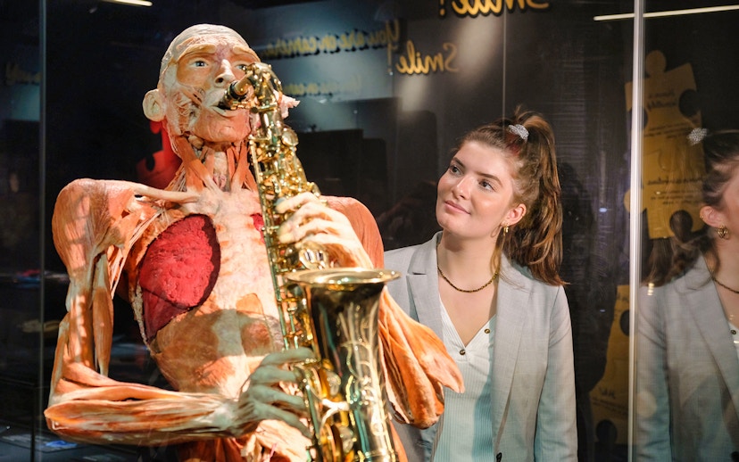 Body Worlds Amsterdam exhibit featuring a human anatomy model playing a saxophone.