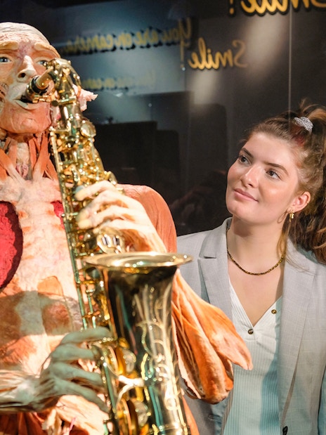 Body Worlds Amsterdam exhibit featuring a human anatomy model playing a saxophone.
