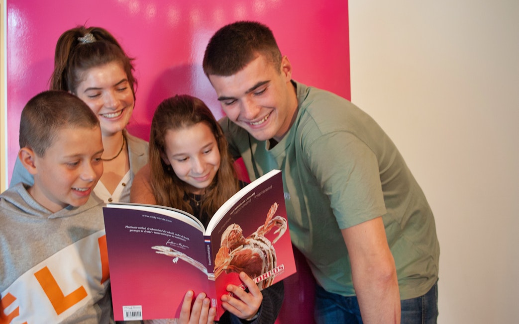 Group of people reading a Body Worlds book at The Happiness Project in Amsterdam.