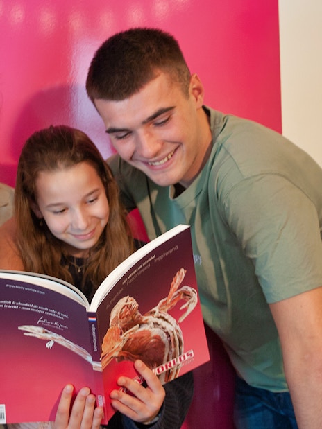 Group of people reading a Body Worlds book at The Happiness Project in Amsterdam.