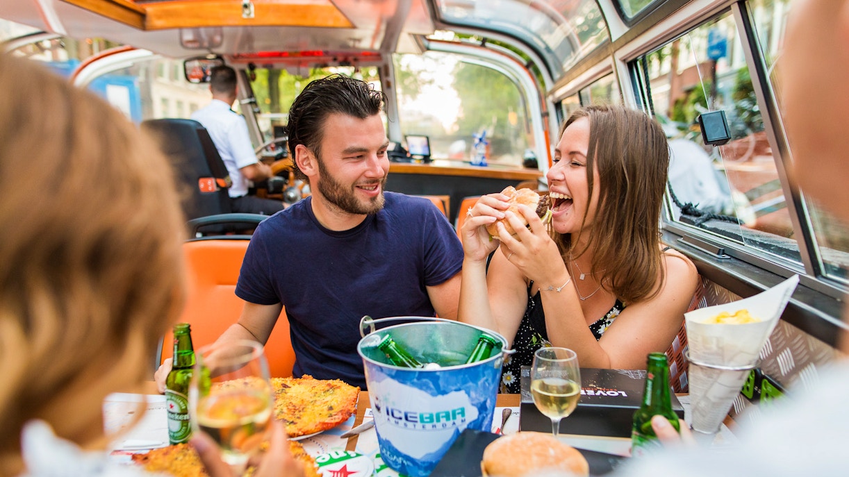 Couple enjoying pizza and drinks on an Amsterdam canal cruise.