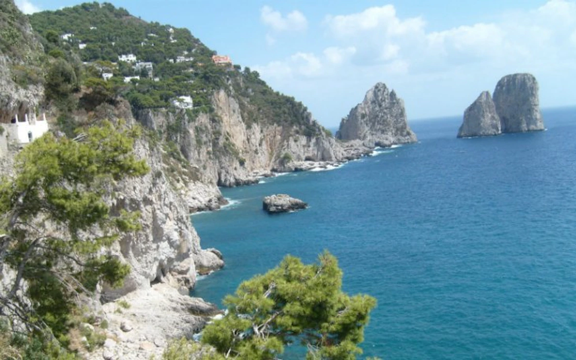 Capri coastline with Faraglioni rock formations, view from a day trip from Rome.