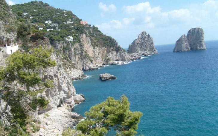 Capri coastline with Faraglioni rock formations, view from a day trip from Rome.