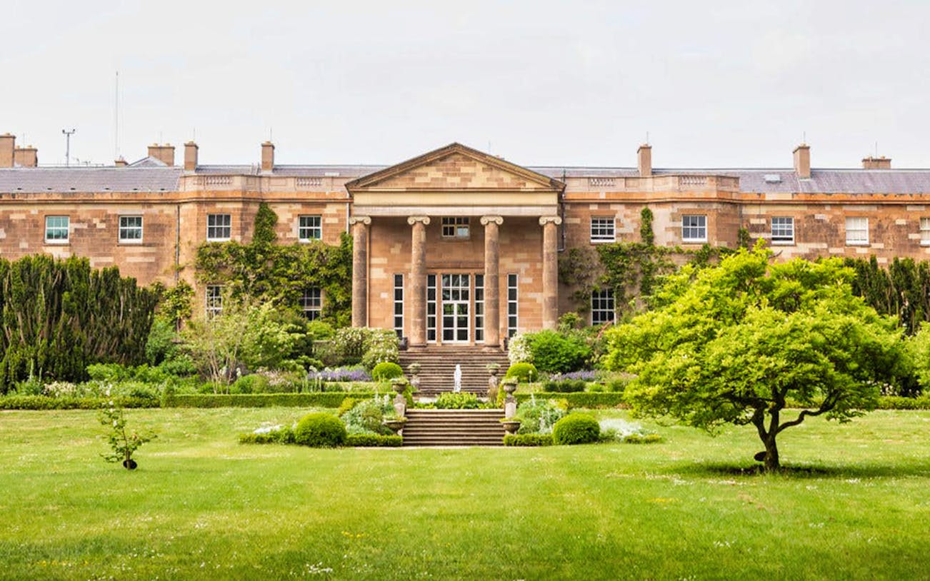 Hillsborough Castle facade with lush gardens and greenery in Northern Ireland.