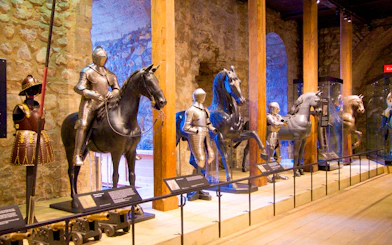 Medieval armor display with knights on horseback at a historical museum.