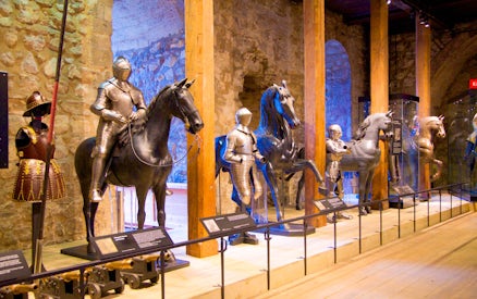 Medieval armor display with knights on horseback at a historical museum.