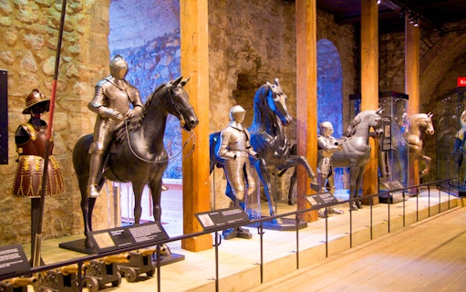 Medieval armor display with knights on horseback at a historical museum.