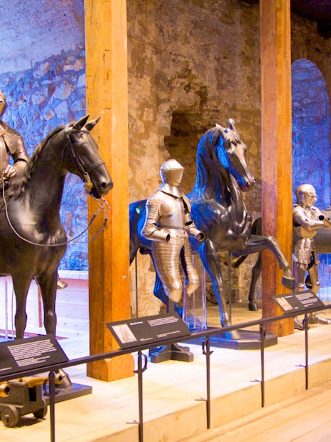 Medieval armor display with knights on horseback at a historical museum.