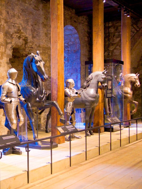 Medieval armor display with knights on horseback at a historical museum.