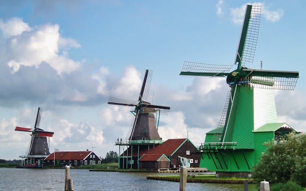 Windmills by the water in Zaanse Schans, Netherlands, part of the Amsterdam: Windmills, Edam and Volendam Tour.